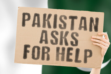 The phrase " Pakistan asks for help " on a banner in men's hand with blurred Pakistani flag on the background. Battle. Combat. Tension. Voice. Aggression. Violence. Relationship. Society. Relation