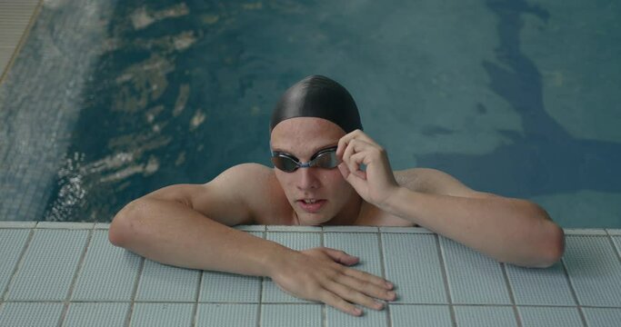Young man in goggles on the pool border