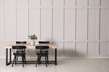 Stylish dining room interior with wooden table and chairs near molding wall, space for text