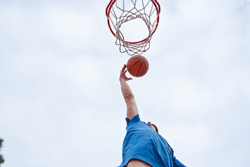 young Caucasian man dunking on an outdoor basketball court. concept of sport