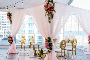 Wedding reception venue A large wedding arch covered with pink cloth decorated with flowers Sea view background 