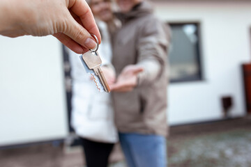 Portrait of young smiling happy family fair-haired woman and dark-haired man moving on new house oundoor side view