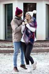 Portrait of two people couple fair-haired woman and man close crossing hands together outdoors in frost weather