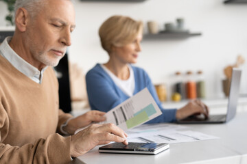 Retired couple planning family budget with laptop and calculator