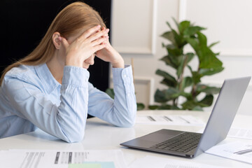 Exhausted woman holding head in hands when working