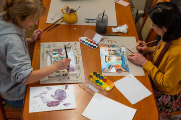 Young women working on watercolor painting of cityscape