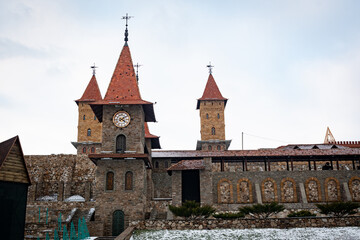 Obraz premium Part of the fortress wall of the castle, with a tower and a large clock tower. Architecture of one of the districts of the Rostov region of the Russian Federation.
