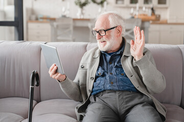 Old elderly senior caucasian man grandfather using digital tablet for social media, talking on...