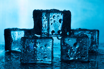 Smooth ice cubes on a blue background. Cold ice with small drops. Slowly melting ice