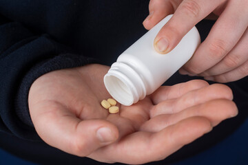 A man pours out pills from a plastic jar.