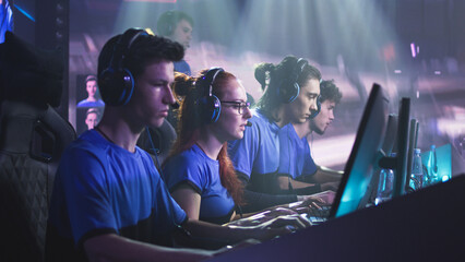 Young and successful men and women professional gamers with coach playing video game on computers...