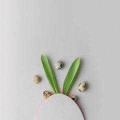 Creative Easter layout with rabbit ears and eggs on a gray background.