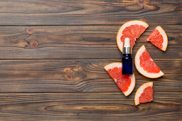 Bottles with Grapefruit fruit essential oil on wooden background. alternative medicine top view with copy space