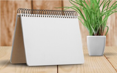 White January 2022 calendar with potted plant on wooden desk on background