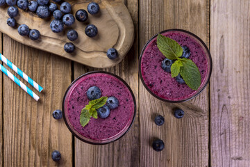 Blueberry cocktail (smothie) in a glass on a rustic wooden background.