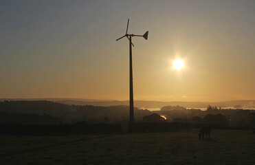 Obraz premium small micro wind turbine generator silhouette at sunrise