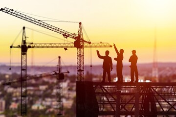 Silhouette of Engineer and worker on building construction site at sunset in evening time.