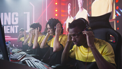 Diverse cyber esportsmen putting on headsets and preparing to play video game during professional championship
