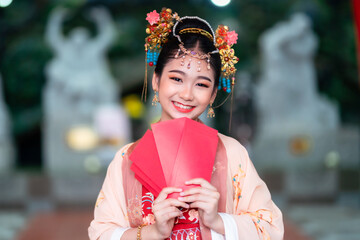 Asian Happy beauty little girl wearing Chinese ancient costumes holding red envelopes decoration...