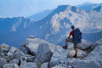 hiker with backpack looking at panorama in high mountain