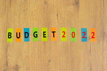 Business concept of budget planning 2022. Words Budget 2022 on colored papers. Beautiful wooden table, wooden background. Business and budget 2022 happy new year concept. Copy space.
