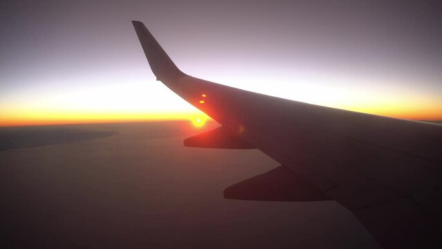 Sunrise from porthole plane, wing view from airplane window, silhouette plane on rising of the sun
