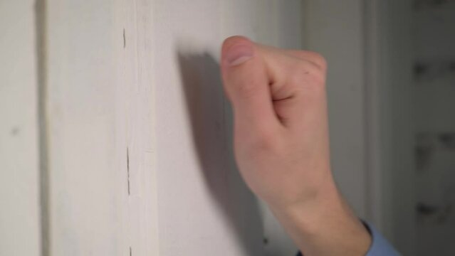 Male hand knocking on the door close-up