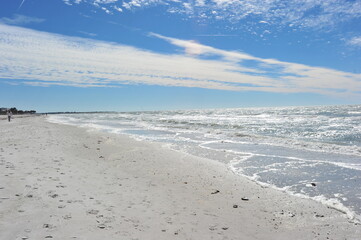 Fototapeta na wymiar light sand beach and sea white waves blue sky