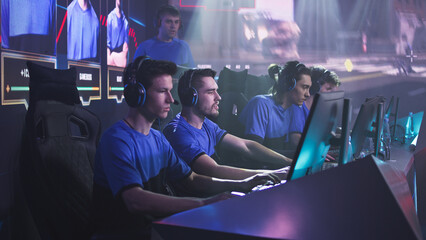 Aggressive esportsman gamer player screaming and breaking keypad while sitting amidst upset teammates after loss in video game during professional tournament © Framestock