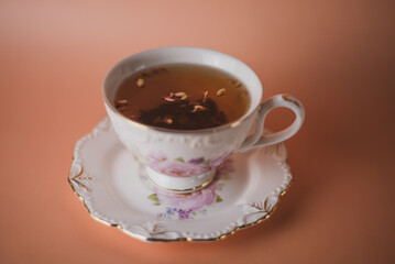 white pink cup with flowers with black tea with tea petals