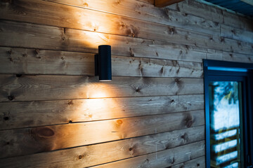 Bright street lamp with double light. Lighting on the streets near the house. Wooden walls of the...