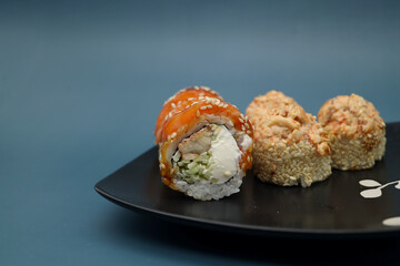 Philadelphia sushi with cheese and cucumbers and Cold sesame roll on black plate