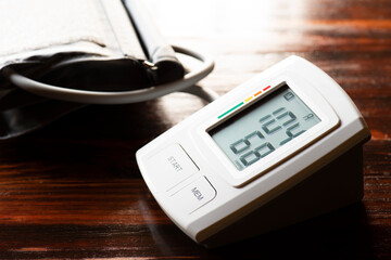 Instrumento electrónico para medir la presión arterial, sobre una mesa y luz natural proveniente...