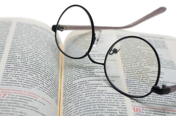 Glasses lying on the Bible in Polish isolated on a white background