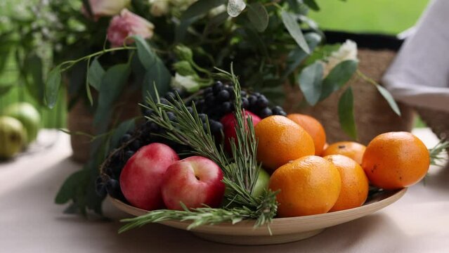 A fruit plate. Various fruits with rosemary on the table. Black grapes, nectarines, tangerines and green apples. 