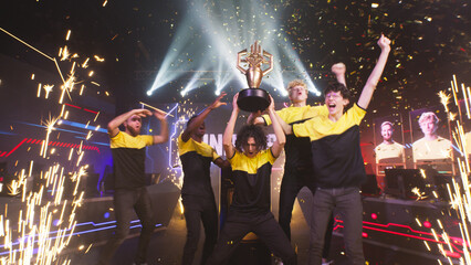Cheerful diverse esports teammates gamers with golden cup screaming in excitement and celebrating...
