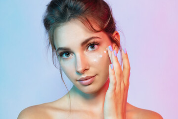 Beautiful girl with moisturizing cream in  neon light. Beauty and skincare concept.