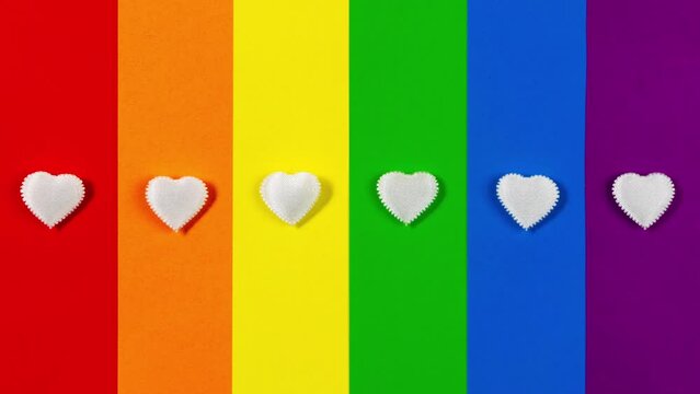 4k Six small white hearts are flashing on LGBT flag background. LGBTQ community, sexuality and gender identity concept. Stop motion animation. Gay pride. Lesbian, gay, bisexual, transgender social mov