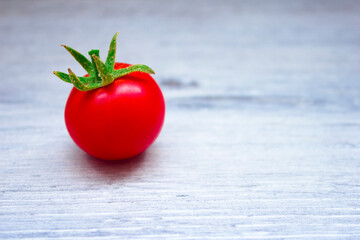 One red cherry tomato with a green tail