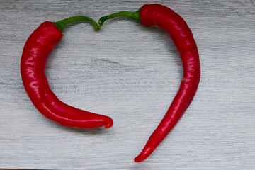 Two red bitter peppers lie in the shape of a heart.