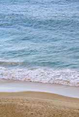 Waves of the blue ocean splashing on the sandy beach
