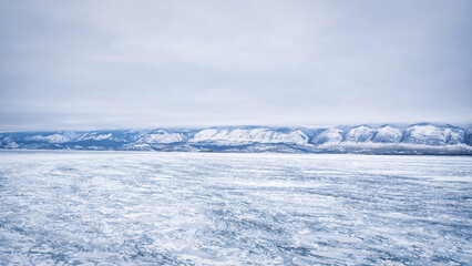 Ice of Lake Baikal in the early morning on the background of ice and mountains.