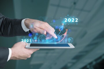 Businessman hand holding tablet showing graph economic growth target success. Plan business growth in year 2022 concept.