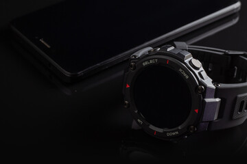 Black smart watch on the smartphone. Closeup, selective focus