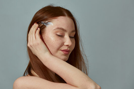 Fox eye lift tape. Redhead young modern girl using trendy eyes lift tapes for foxy look effect. Beauty trend