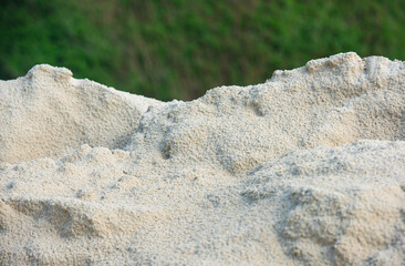 Mound of wet sand after the rain with green background.