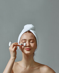 Girl in towel on head use beauty gua sha jade quartz roller for perfect glowing skin. Face lifting anti aging massage