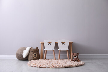 Cute child room interior with furniture and toy near light grey wall