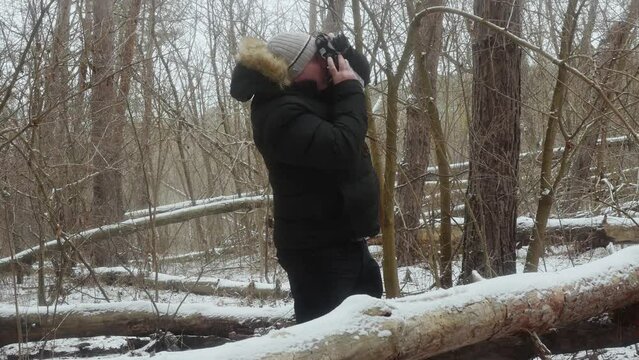 a man in a snowy forest photographs nature on a vintage film camera