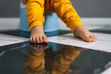 Child sitting on toilet , Low view on his legs hanging with yellow trousers. Training child or...